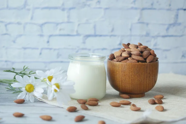Frasco de leche y cuenco de almendras sobre una mesa de madera